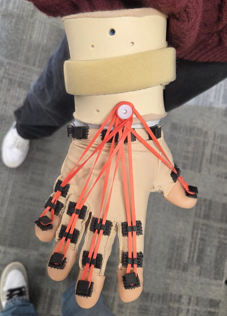 Opened hand with resistance glove component. With red rubber bands on each finger.