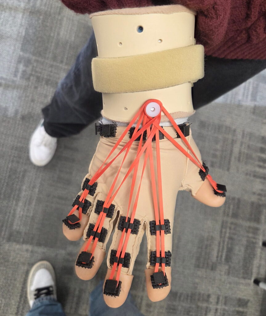 Opened hand with resistance glove component. With red rubber bands on each finger.