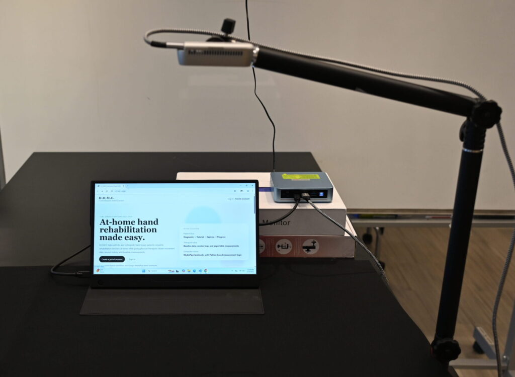 Moniter on a table with a mouse pad, white background, and camera arm holding a camera parallel to the table.