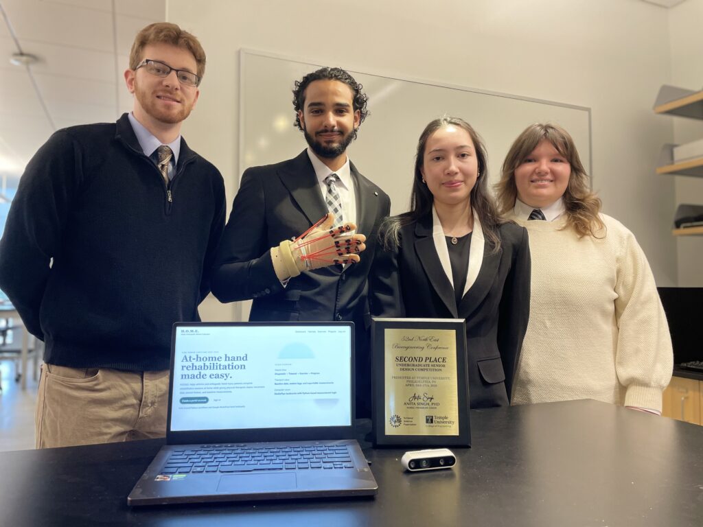 The whole team posing behind the monitor showing the GUI and award from NEBEC.