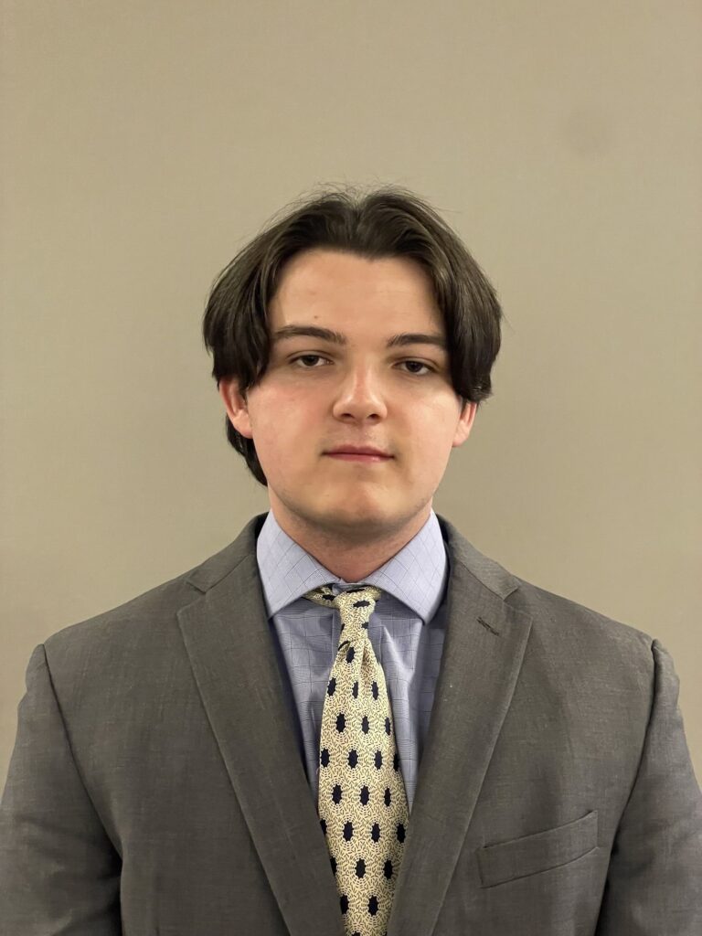 Headshot of Steven Ioannidis smiling at the camera with a gray suit and light yellow tie.